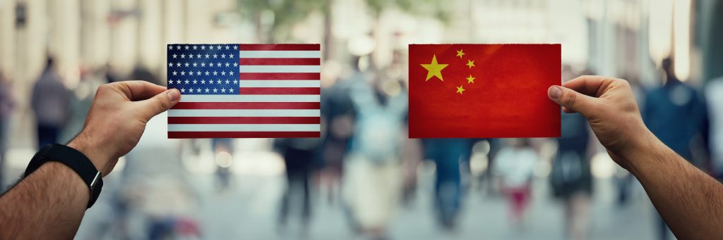 Amerikanische und chinesische Flaggen werden in Händen gehalten.